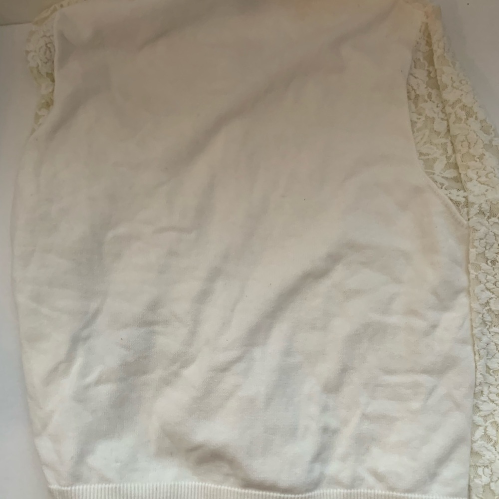 A girls sweater with lace on the front and buttons